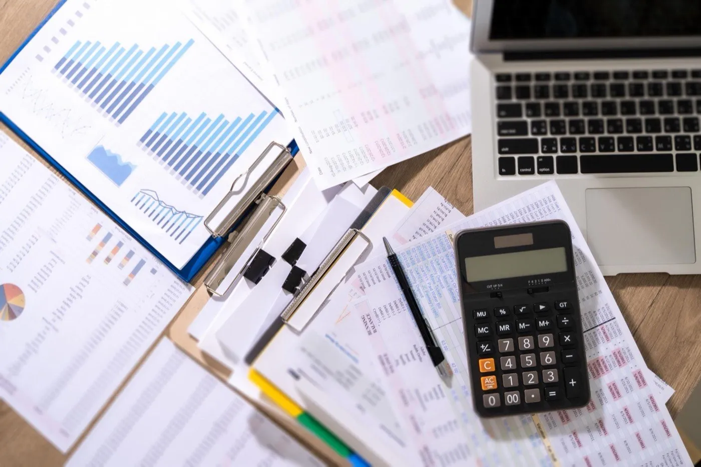 Finance team's desk with reports, calculator and laptop